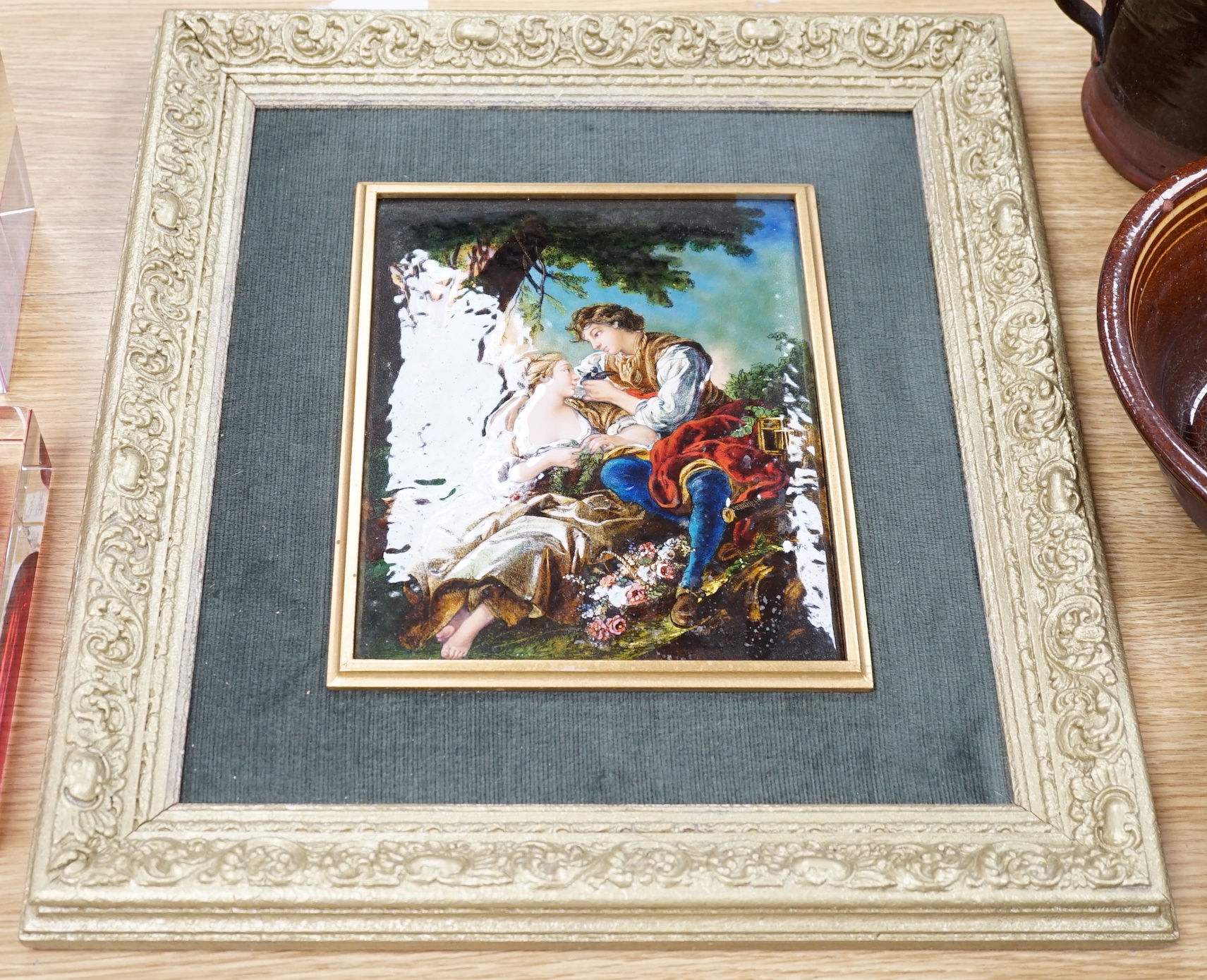 A Limoges enamel plaque, decorated with two lovers wearing 18th century dress before a landscape, housed in a gilt frame, 25cm x 19cm excluding the frame